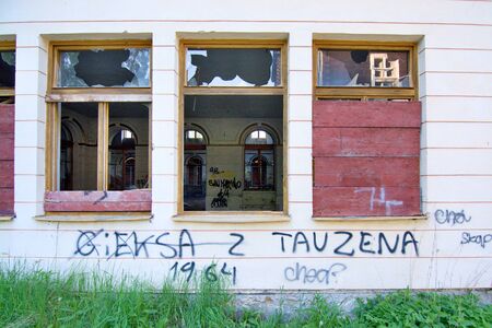 Devastated house with broken windows which are blinded by wooden boardsの写真素材