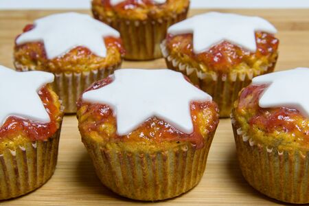Basic muffins with red strawberry marmelade and white start placed on wooden boardの写真素材
