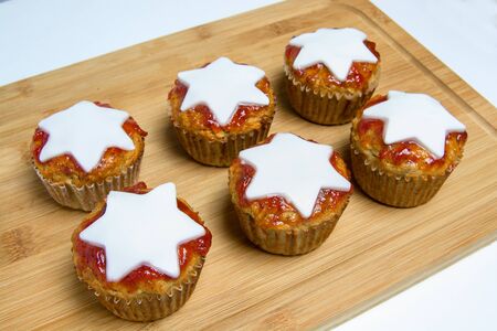 Basic muffins with red strawberry marmelade and white start placed on wooden board, isolated on white backgroundの写真素材