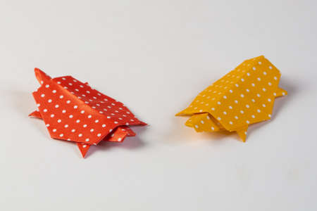 Two origami turtles made from red and yellow paper with white dots, isolated on white backgroundの写真素材