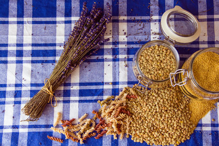 Lentils, couscous, pasta, two jars and lavender on the table in the kitchenの写真素材