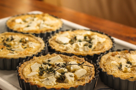Delicious sheep cheese and onion tarts with a thyme sprig on topの写真素材