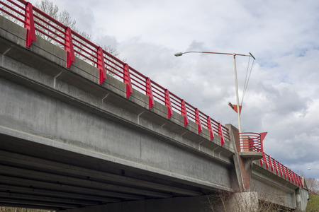 View of a concrete road bridge with a street lamp and red railingの写真素材