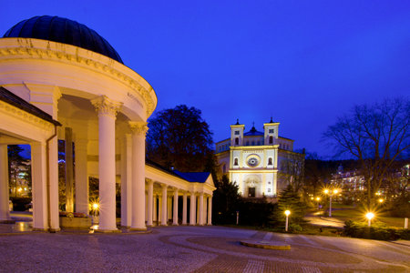 Colonnade of mineral water spring and catholic church at night - Marianske Lazne (Marienbad) - great famous Bohemian spa town in the western part of the Czech Republicのeditorial素材