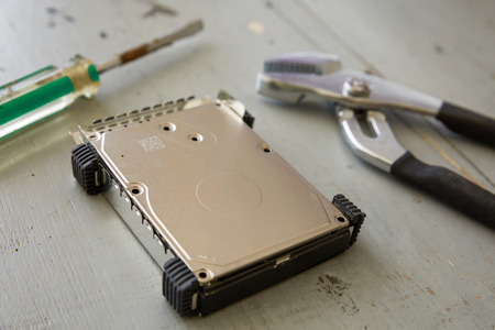 Broken and Destroyed Hard Drive Disk and Tools on Wooden Table.の写真素材