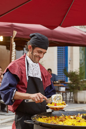 Man smiling, preparing and serving paella (typical spanish meal) in the street of Cartagena in Spain.のeditorial素材