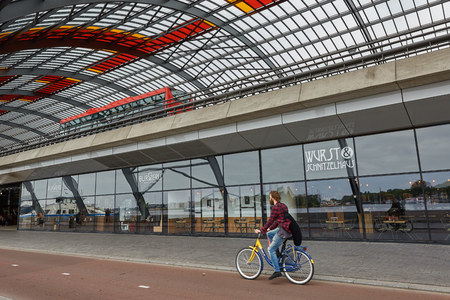 AMSTERDAM, NETHERLANDS - SEPTEMBER 21, 2017: Cyclist riding a bike along the train station in Amsterdam Netherlands.のeditorial素材
