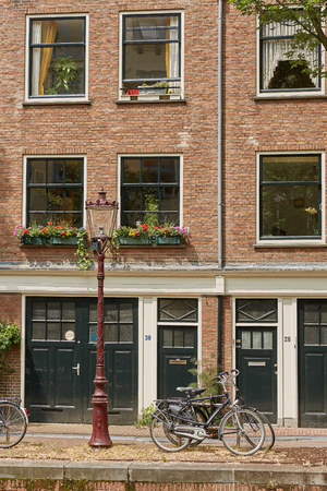 AMSTERDAM, NETHERLANDS - SEPTEMBER 21, 2017: Bicycle as popular way of transport in Amsterdam Netherlands parked and locked in front of traditional house in Holland.のeditorial素材