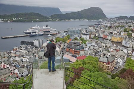 ALESUND, NORWAY - MAY 29, 2017: Man photographing city of Alesund in Norway from look out point of Fjellstua.のeditorial素材