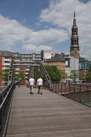 Hamburg, Germany - May 22, 2017: People crossing bridge and city life in Hamburg in Germany with St. Catherine's church in the background.のeditorial素材