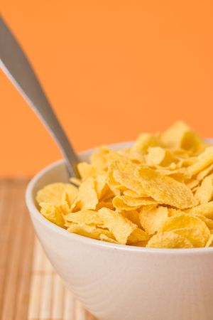 cornflakes in bowl on orange backgroundの写真素材