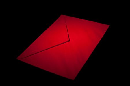 closed envelope with red spot light on black backgroundの写真素材