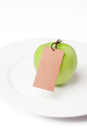 the photo shot of green apple with label on white plateの写真素材