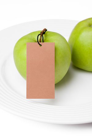 the photo shot of green apples with label on white plateの写真素材