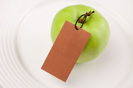 the photo shot of green apple with label on white plateの写真素材