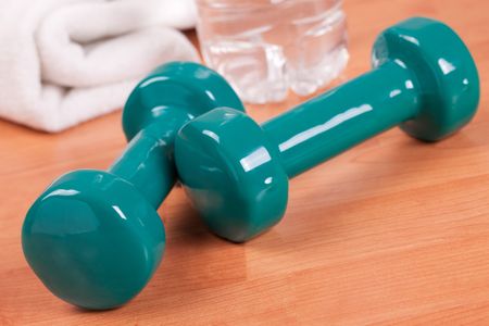 the green dumbells with towel on wooden backgroundの写真素材