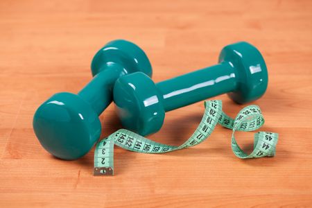the green dumbells with measuring tape on wooden backgroundの写真素材