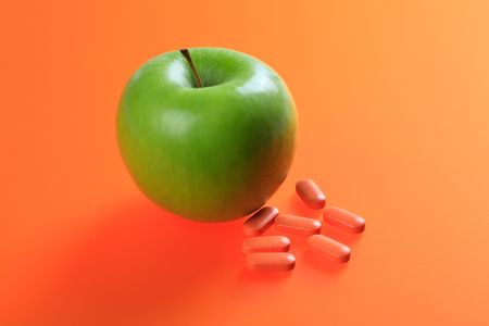 green apple and vitamin pills on color backgroundの写真素材