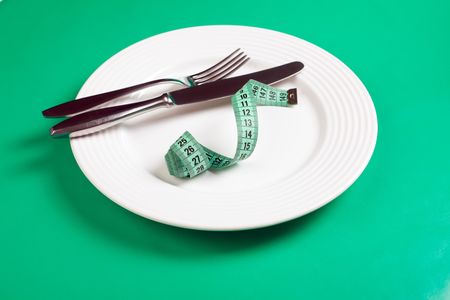 dishes with measuring tape on green backgroundの写真素材