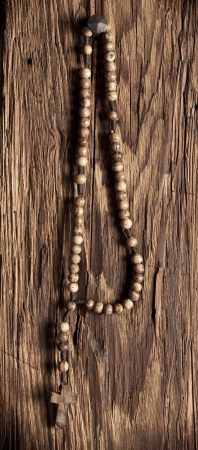 Wooden rosary beads hanging on the old wooden backgroundの写真素材