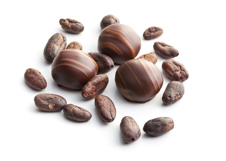 chocolate pralines and cocoa beans on white background