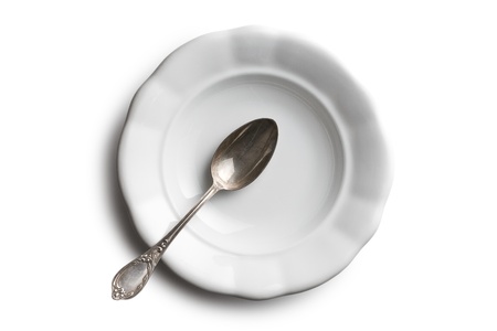antique ceramic plate and silver spoon on white backgroundの写真素材