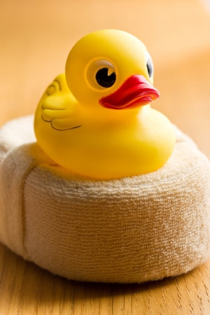 yellow bath duck on wooden tableの写真素材