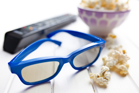 3d glasses with popcorn on white wooden table