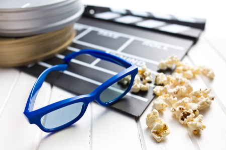 3d glasses with clapperboard and popcorn on white wooden tableの写真素材