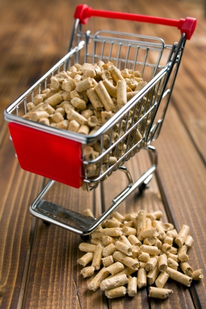 wooden pellets in shopping cart on wooden backgroundの写真素材