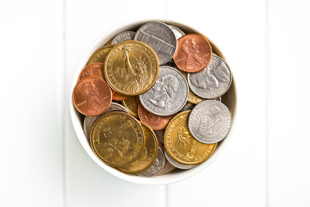 U.S. coins in ceramic bowl on wooden tableの写真素材