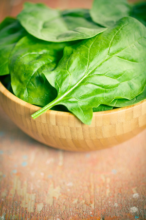 green spinach leaves in wooden bowlの写真素材