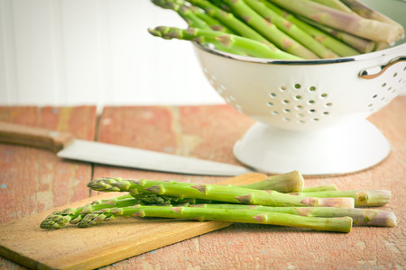 green asparagus in colander on old wooden backgroundの写真素材