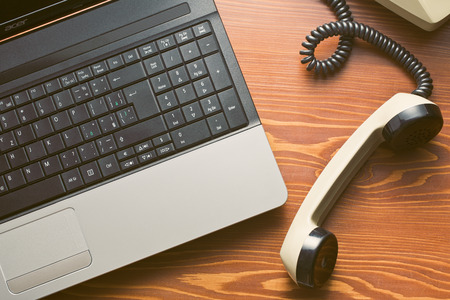 retro phone and modern laptop on wooden table