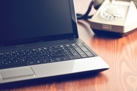 laptop and retro phone on office tableの写真素材