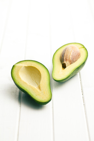 halved avocados on white wooden table