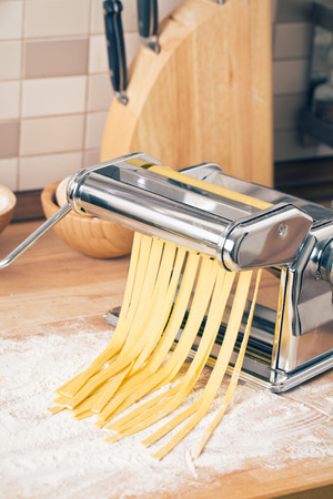 fresh pasta and pasta machine on kitchen tableの写真素材