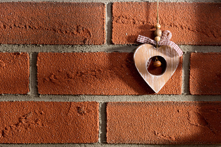 the wooden heart hanging on a brick wallの写真素材