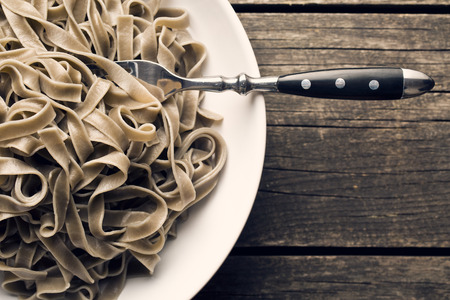 cooked black tagliatelle pasta on plateの写真素材
