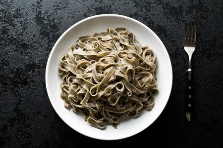cooked black tagliatelle pasta on plateの写真素材