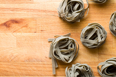 black tagliatelle pasta on wooden table