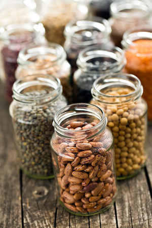 various dried legumes in jars on old tableの写真素材
