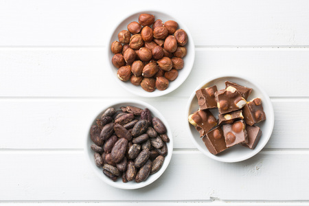 chocolate, hazelnuts and cocoa beans on kitchen tableの写真素材