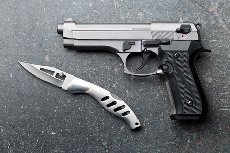 handgun and knife on old background