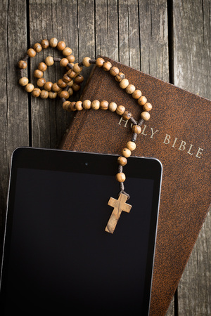 wooden rosary beads with computer tablet on old wooden tableの写真素材