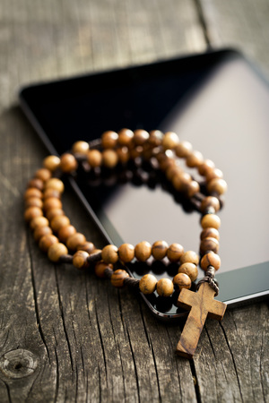 wooden rosary beads with computer tablet on old wooden tableの写真素材