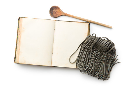cookbook and black noodles with squid sepia ink on white backgroundの写真素材