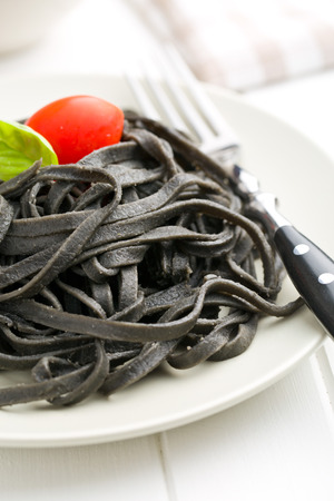 cooked black noodles with squid sepia ink on plateの写真素材