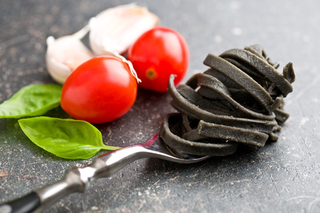 noodles, garlic, tomatoes and basil leaves on old kitchen tableの写真素材
