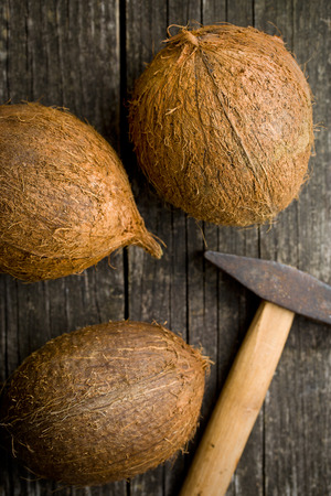 whole coconuts and hammer on old wooden table